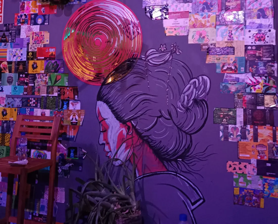 Mural de una mujer con kimono rodeado de etiquetas de cerveza en la pared
